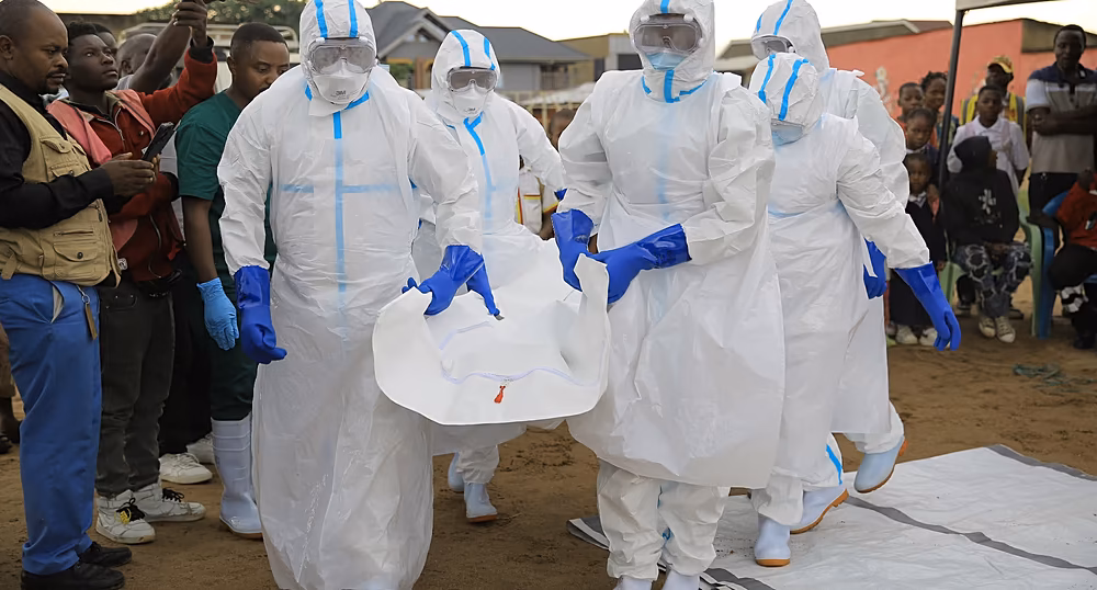 Healthcare workers in protective equipment carry the body of doctor Victor Kingombe during his funeral in Kisangani