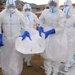 Healthcare workers in protective equipment carry the body of doctor Victor Kingombe during his funeral in Kisangani