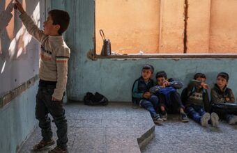 Syrian child walking home from school through a damaged area of Damascus